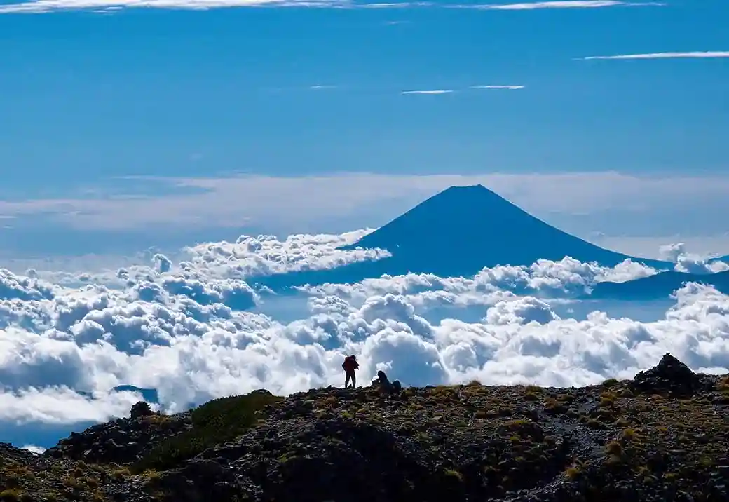 Hikers overlooking Mt Fuji above the clouds in Yamanashi Japan